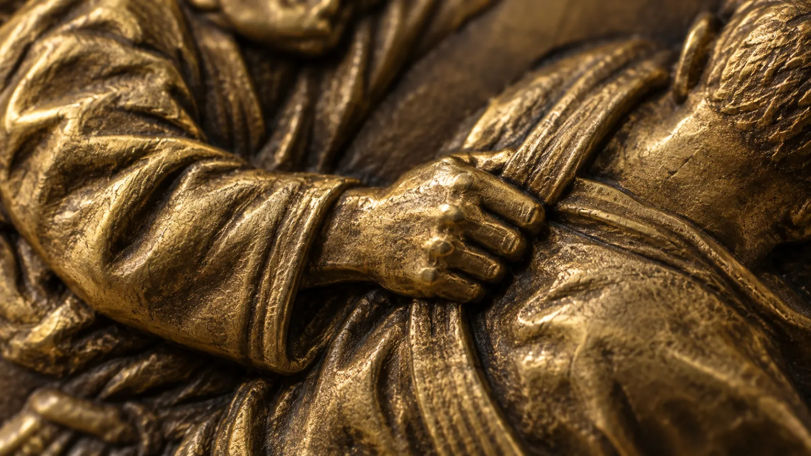 Macro of a die-cast judo medal: the raised relief of a judoka gripping an opponent's collar, lit from the side